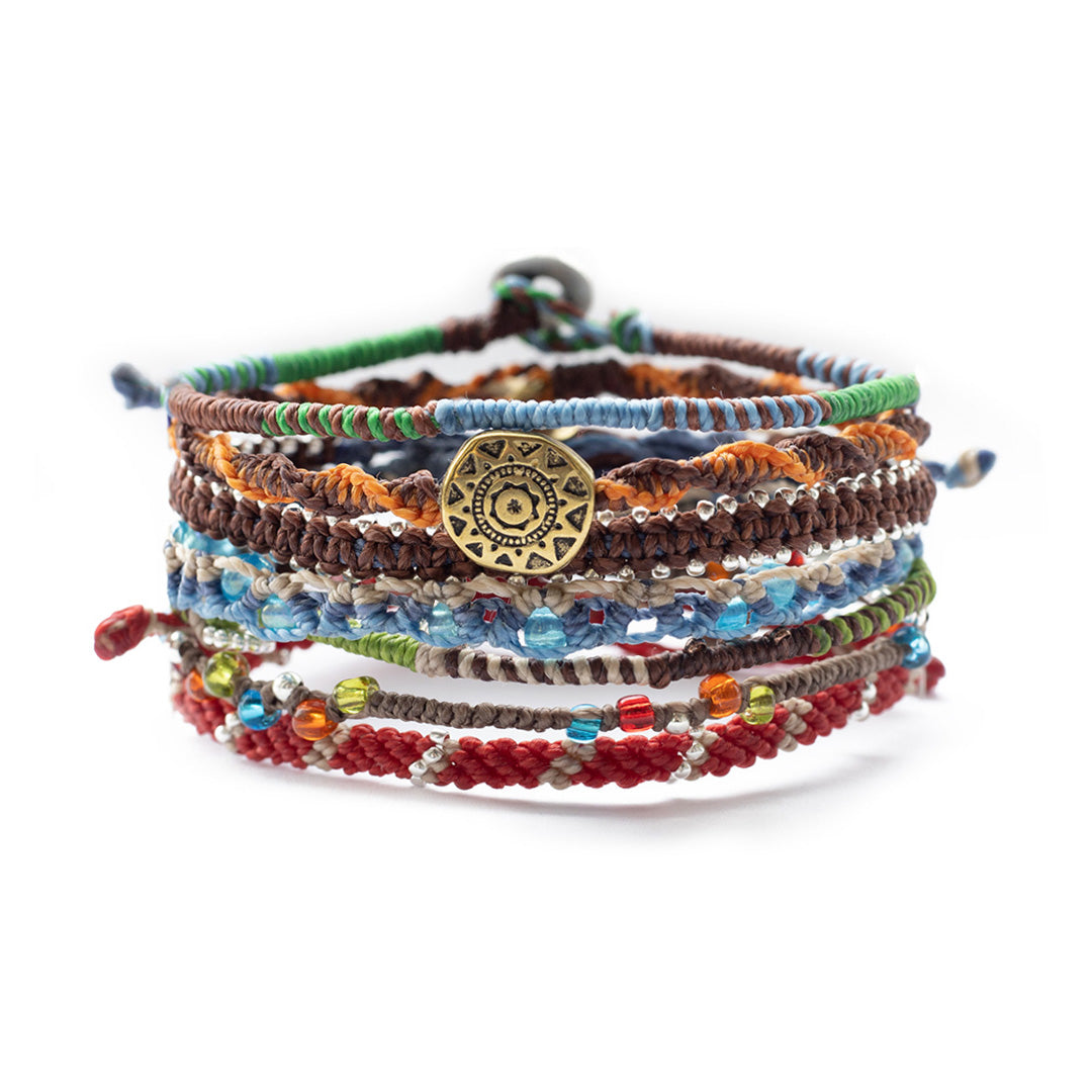 Colorful, intricately braided bracelets stacked together, with beads and a circular pendant.